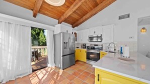 A kitchen with white cabinets, a yellow countertop, a stainless steel refrigerator, an oven, and a microwave.