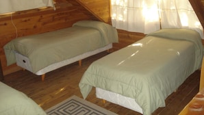 A small, cozy attic bedroom with two single beds, wooden walls, and a sloped ceiling. - Patagonia Sin Fronteras (San Carlos de Bariloche)