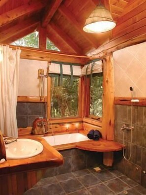A wooden cabin bathroom with a bathtub, shower, and sink. - Patagonia Sin Fronteras (San Carlos de Bariloche)