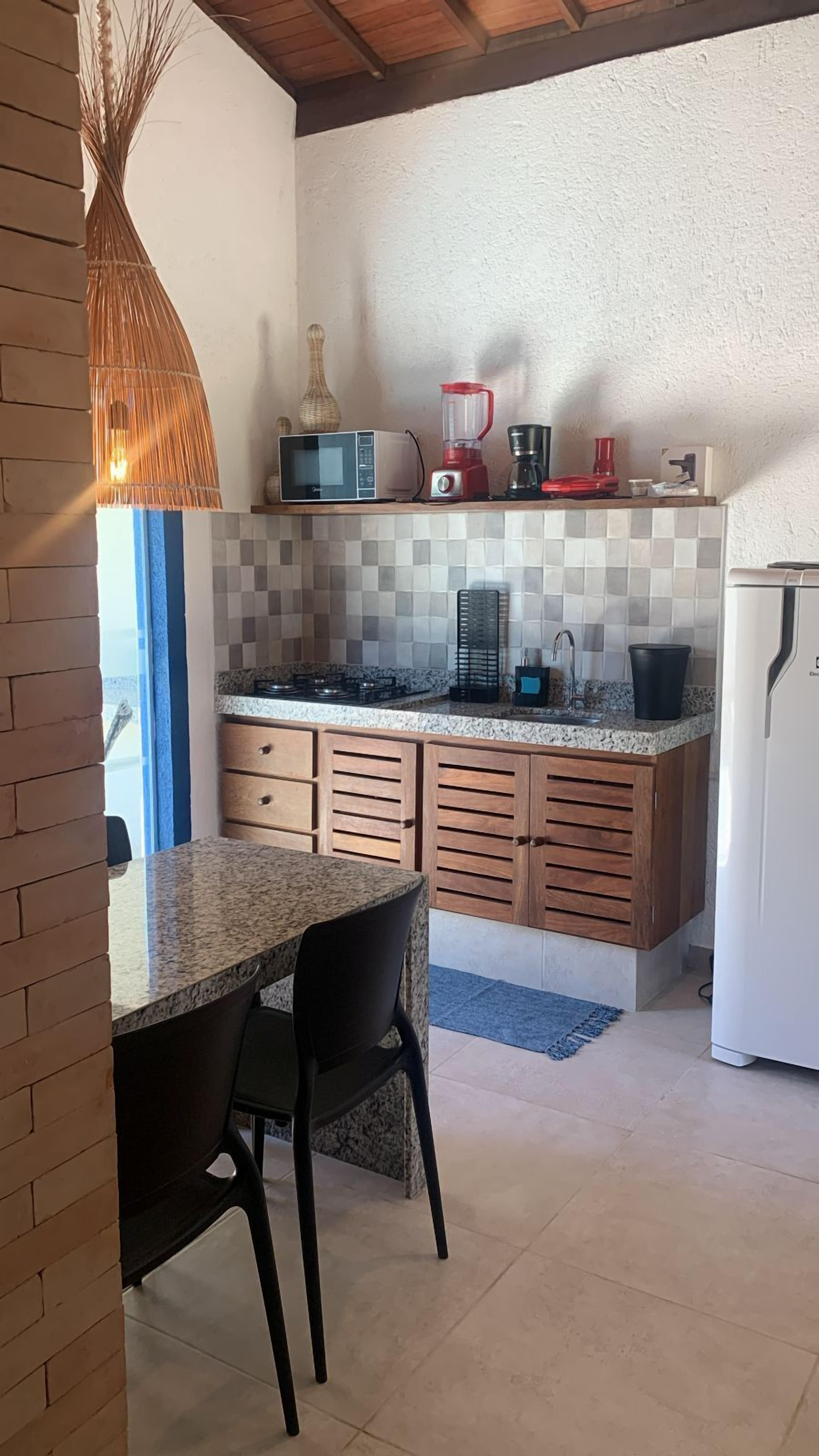 Une cuisine dotée d’un plan de travail en granit, de meubles en bois, d’un four à micro-ondes, d’une machine à café et d’un réfrigérateur.