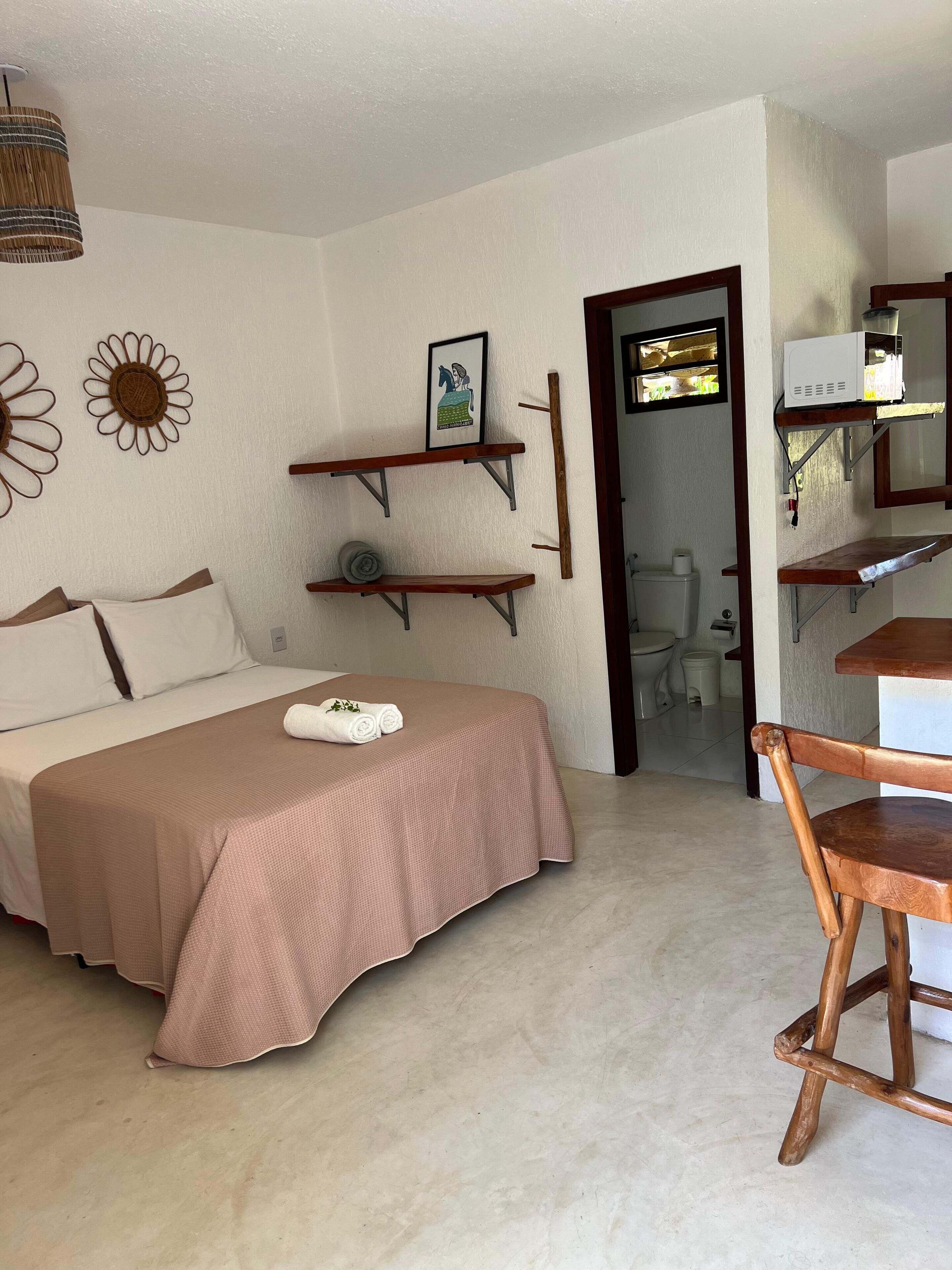 Ein Schlafzimmer mit einem Bett, einem Holzstuhl, einem Regal mit einem Bild und einem kleinen Tisch.