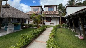 A resort with a central pathway, thatched-roof structures, and white buildings with red trim.
