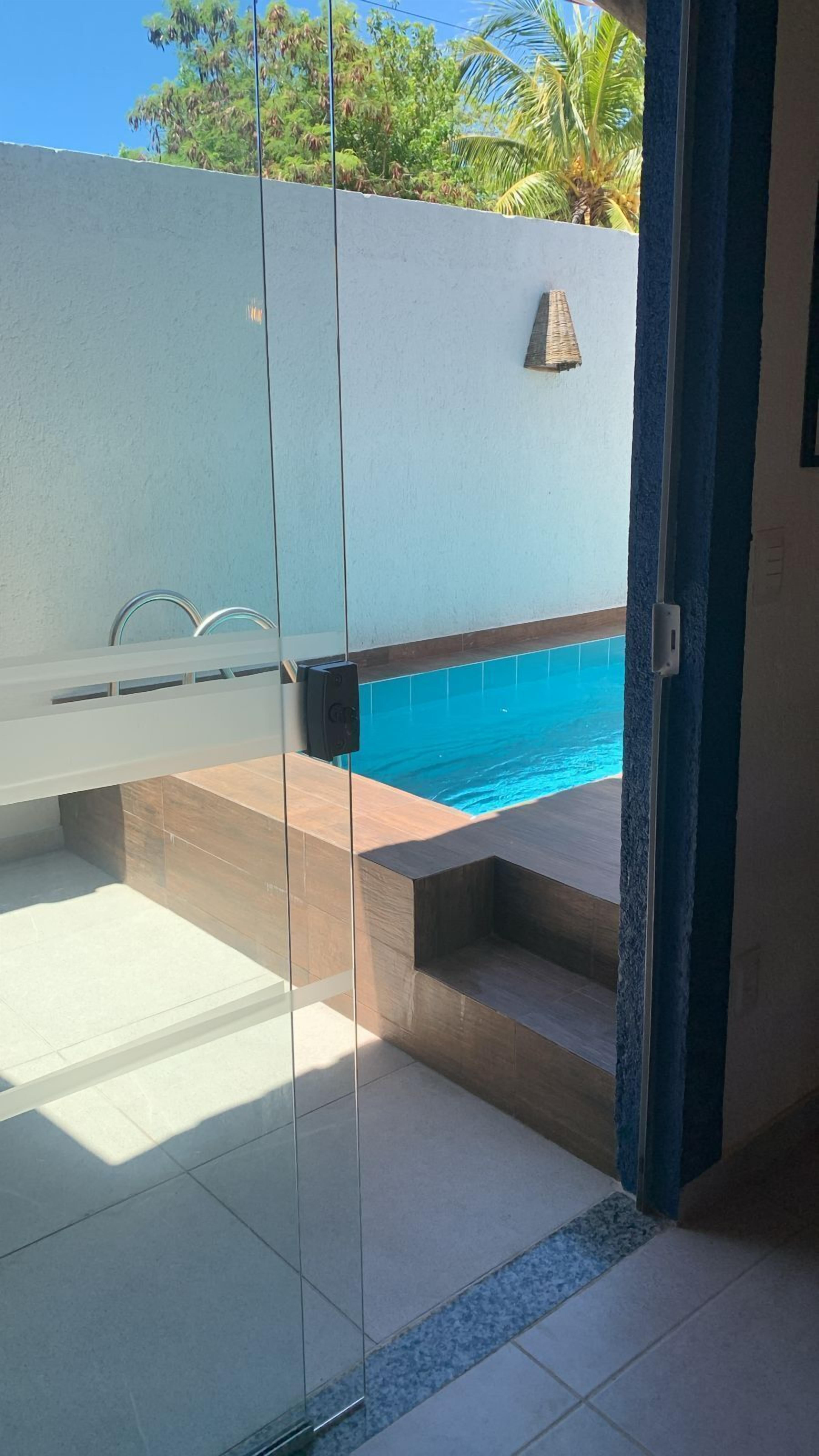 Ett modernt badrum med en duschkabin i glas, ett inbyggt badkar och en liten poolhörna.