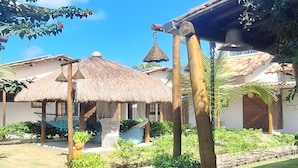 A courtyard with thatched-roof structures, a hammock, and a well-maintained garden.