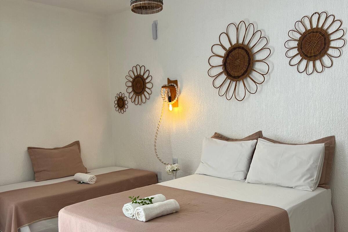 Habitación de hotel con dos camas, una lámpara colgante y decoración en la pared.