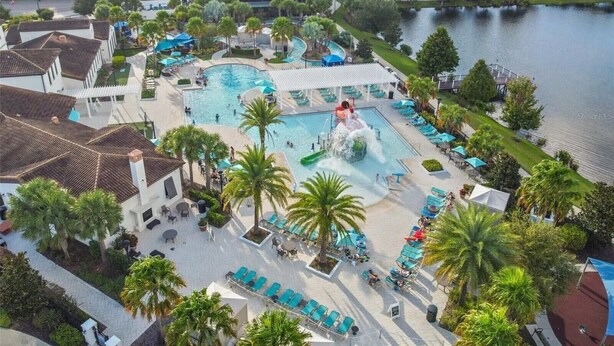 A resort with a large pool, water slides, and a lake view. - 9BR Home w/ Private Pool, Game Room, & Free Resort Access (Kissimmee)