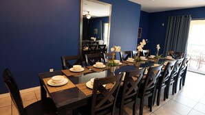 A dining area with a long table, chairs, and a mirror on the wall. - 9BR Home w/ Private Pool, Game Room, & Free Resort Access (Kissimmee)