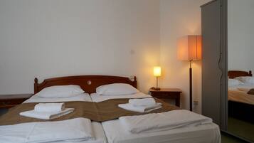 A hotel room with a wooden bed, white linens, a bedside lamp, and a mirror.