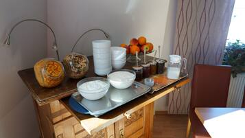 A breakfast bar with various food items, including bowls of yogurt, a fruit bowl, and jars of spreads.