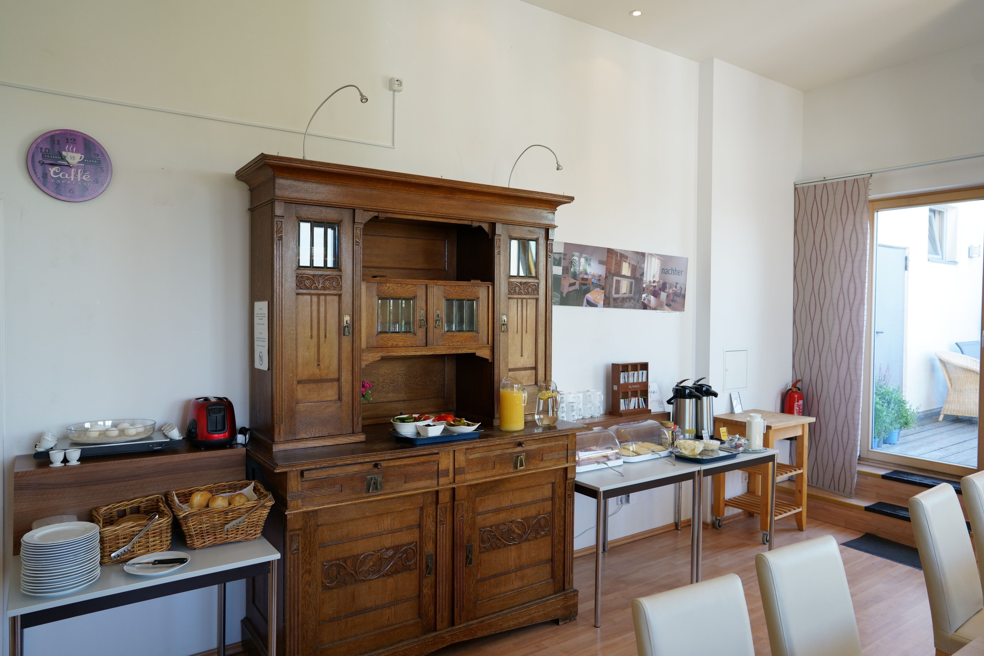 A kitchen with wooden cabinets, a dining table, and a breakfast setup including a toaster and a fruit bowl.