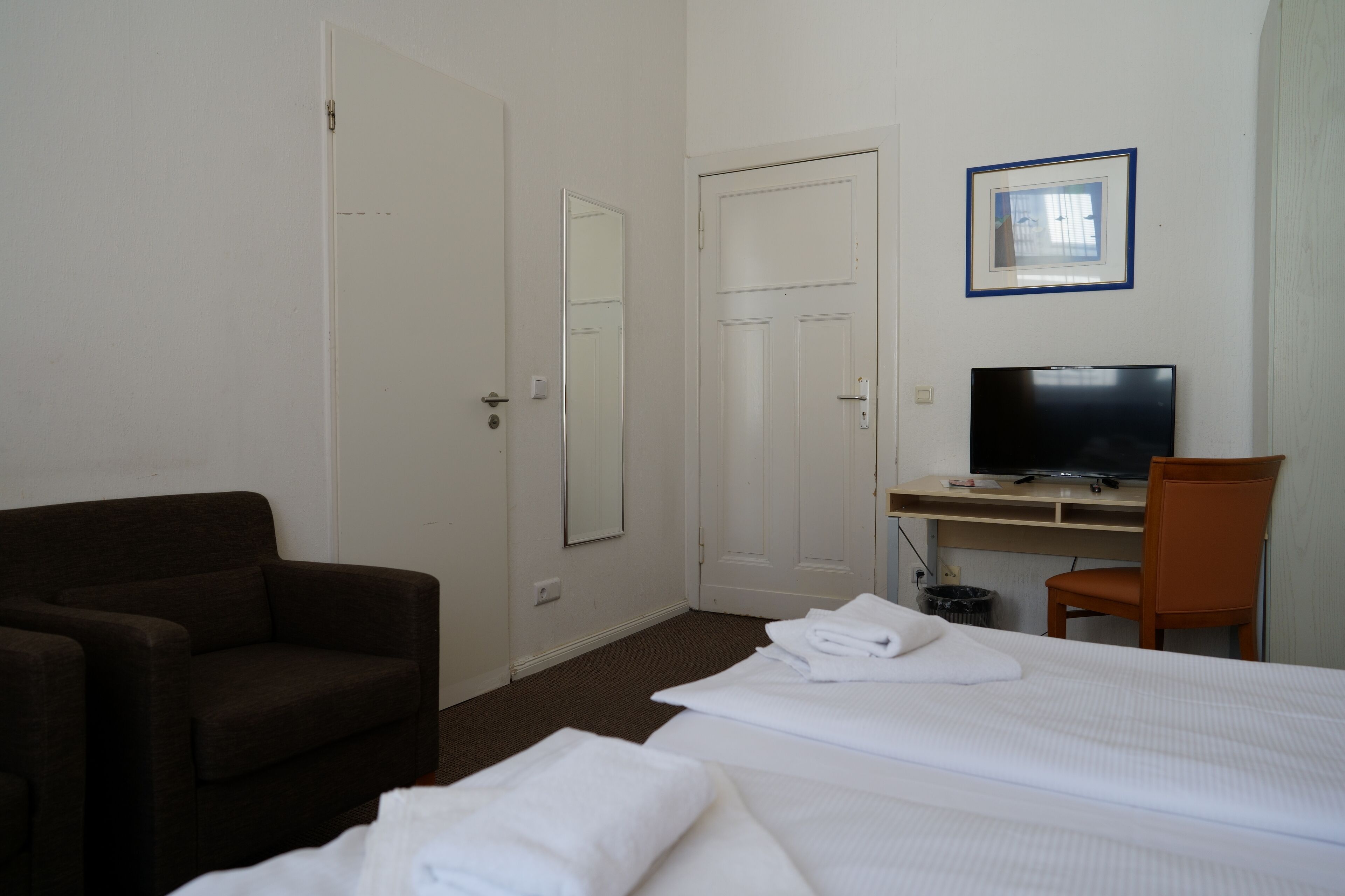 A hotel room with a bed, a desk with a television, a chair, and a couch.