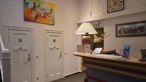 A reception area with a desk, a clock, a world map, and two doors. - Hotel Ambert (Berlin)