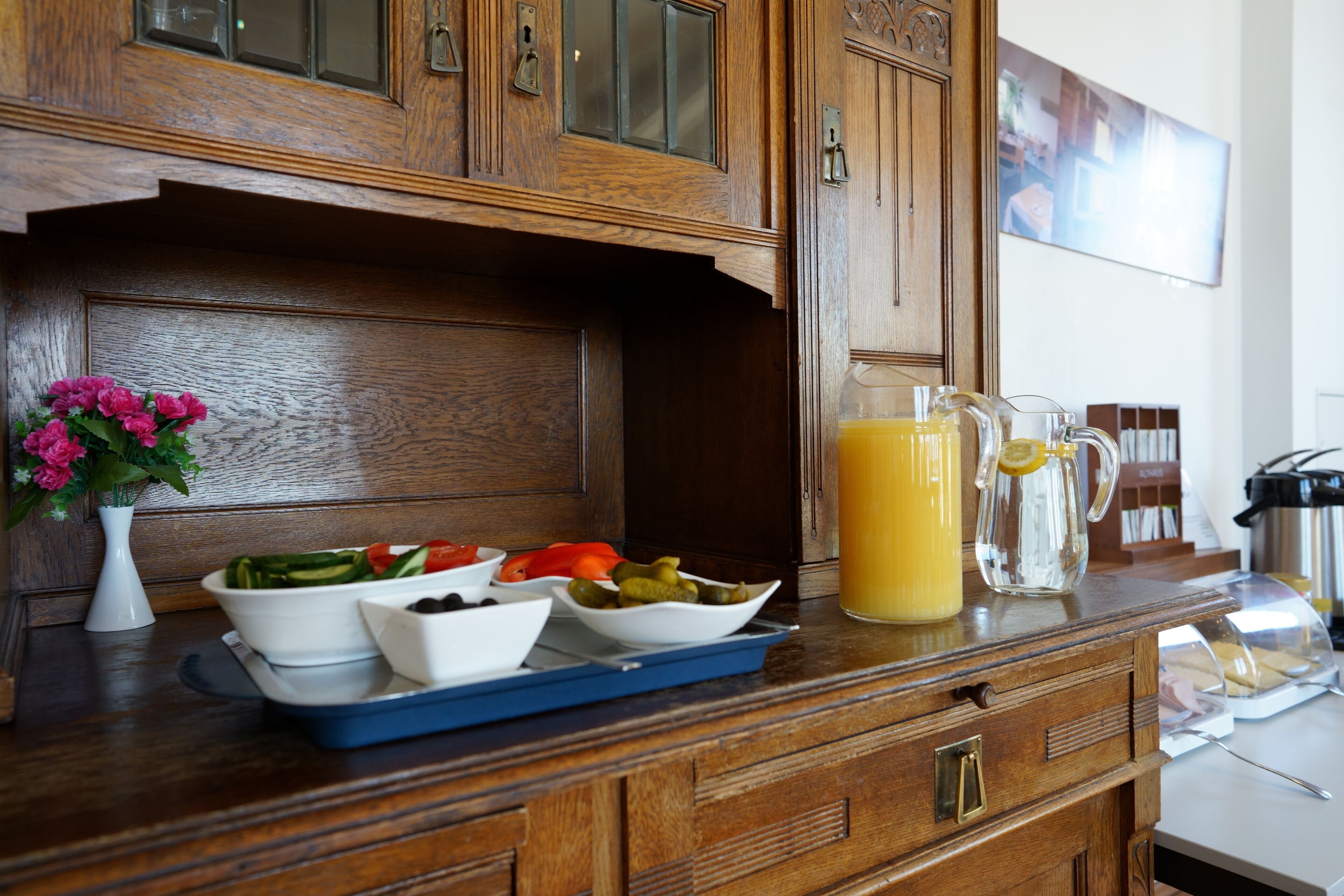 A kitchen counter with wooden cabinets, a vase with flowers, and various bowls of food.