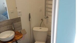 Un baño pequeño con tocador de madera, un lavabo blanco y un inodoro.