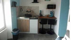Una kitchenette compacta con un lavamanos, estufa, microondas y dos taburetes de bar.