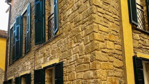 A stone building with multiple windows and shutters.
