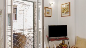 A room with a television on a stand, a door leading outside, and two framed pictures on the wall. - Apartment 'Sole' with Wi-Fi (Cipressa)