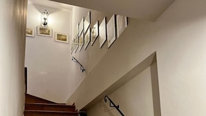 A staircase with wooden steps and black handrails, leading to a landing with framed pictures and a wall-mounted light fixture. - Apartment 'Sole' with Wi-Fi (Cipressa)