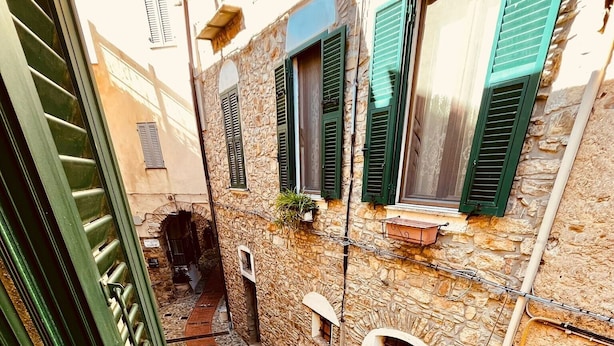 A narrow alleyway with stone buildings, green shutters, and a metal gate. - Apartment 'Sole' with Wi-Fi (Cipressa)