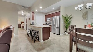A modern kitchen with a central island, stainless steel appliances, and a dining area with bar stools. - Ground Floor 2 BDR With Garage! Heated Comm Pool! (Mesa)