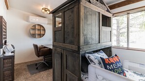 A bedroom with a wooden bunk bed, a desk, and a chair.