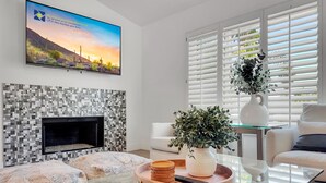 A modern living room with a fireplace, a glass coffee table, and a comfortable seating area. - Juniper Scottsdale (Scottsdale)