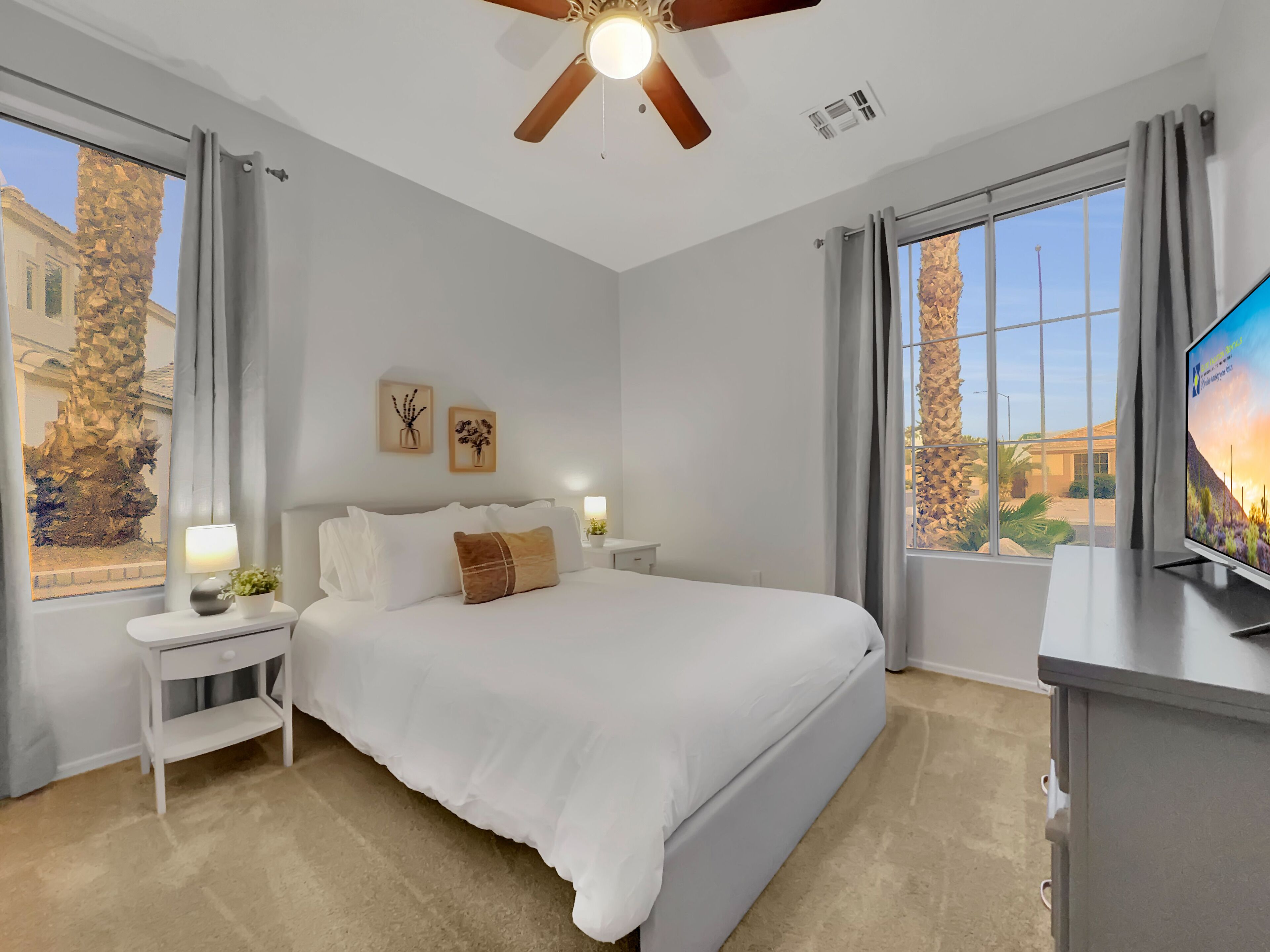 A bedroom with a bed, nightstands, a ceiling fan, and a TV.