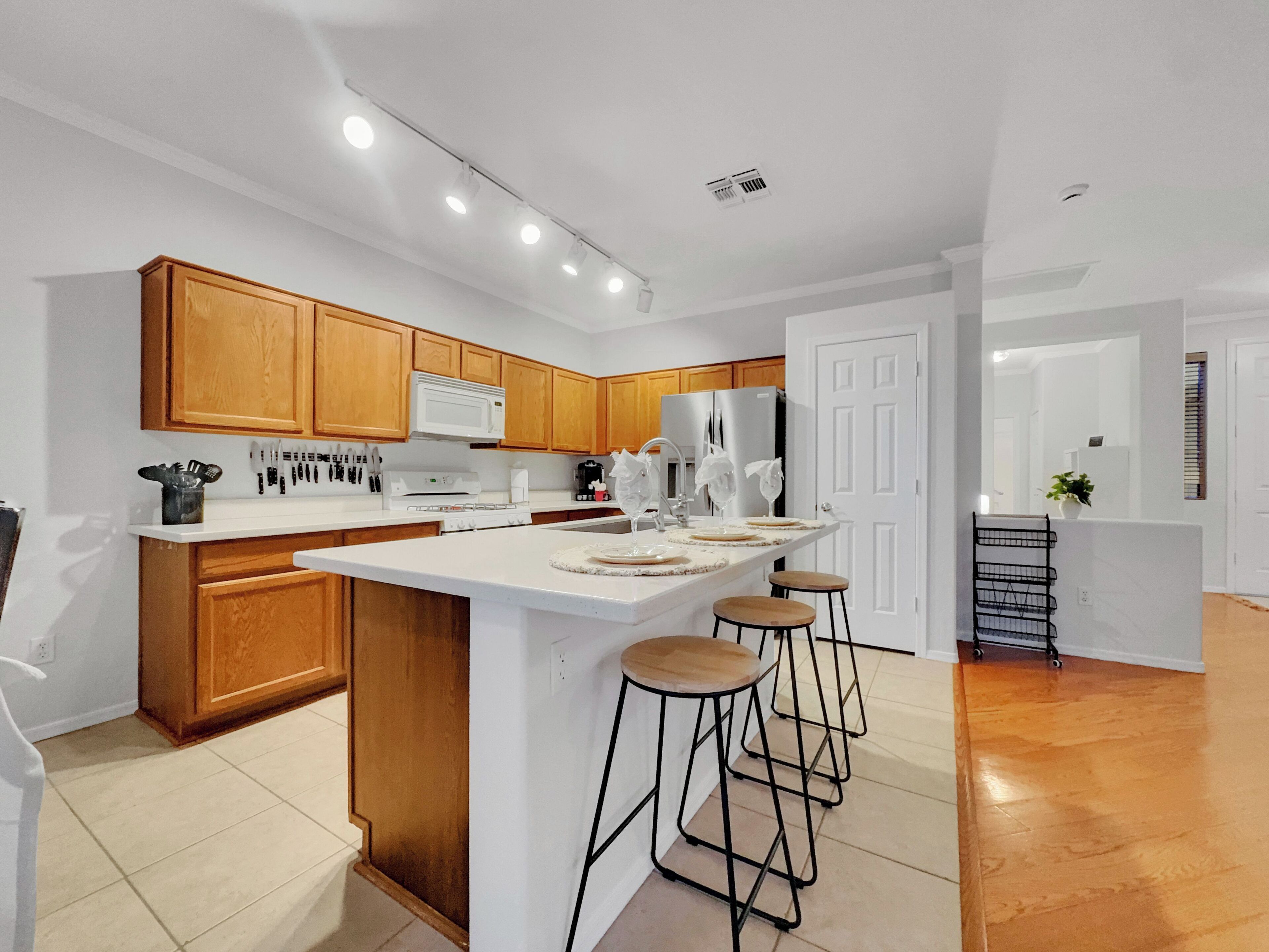 Una cocina moderna con armarios de madera, una encimera blanca y una isla central con taburetes.