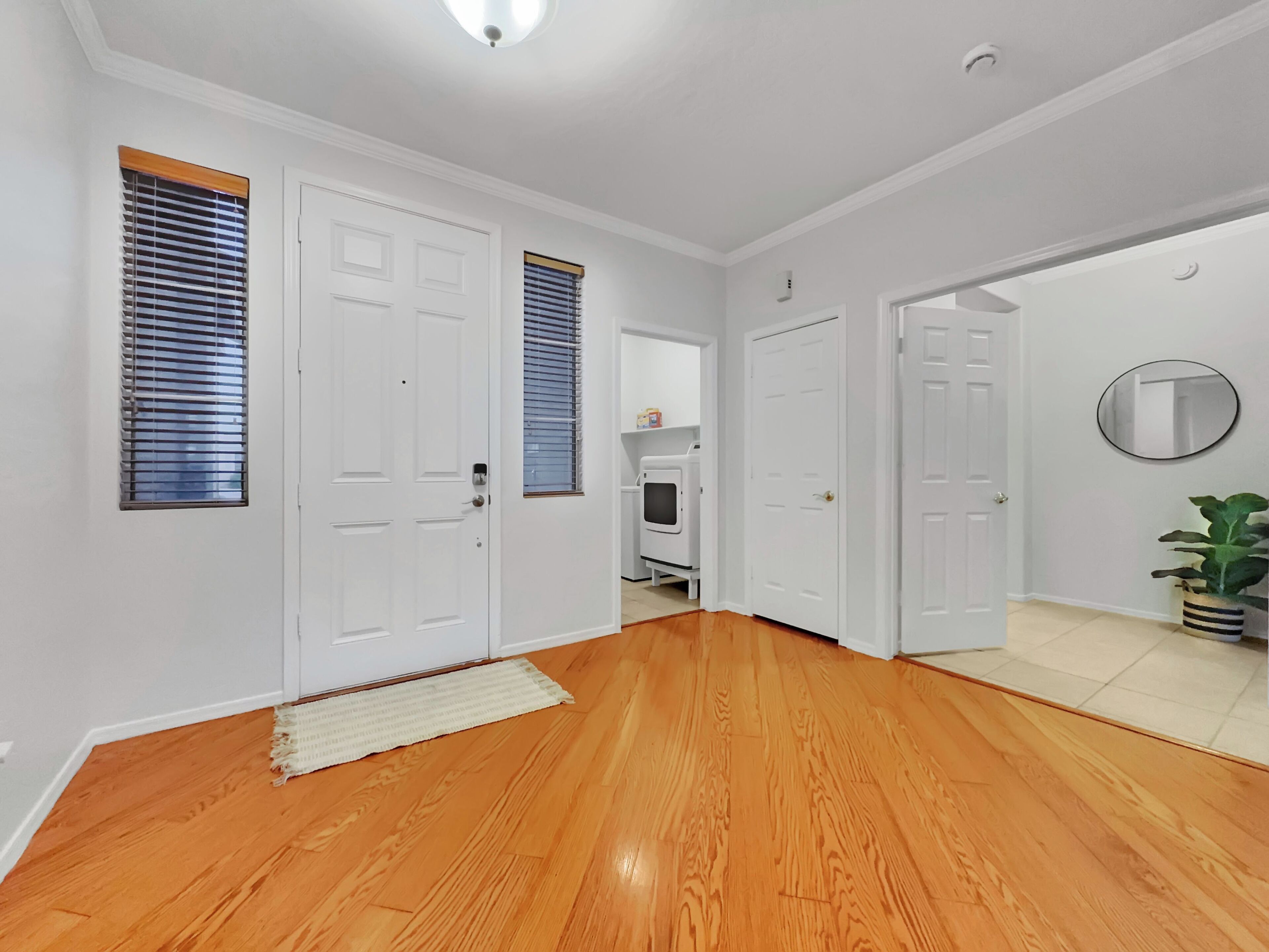 A hallway with wooden flooring, white walls, and two white doors.