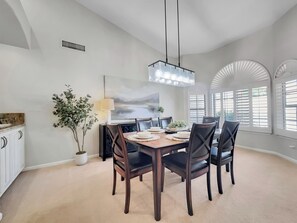A dining area with a wooden table, dark chairs, a hanging light fixture, and a potted plant. - Oleander 2 Chandler/ocotillo (Chandler)