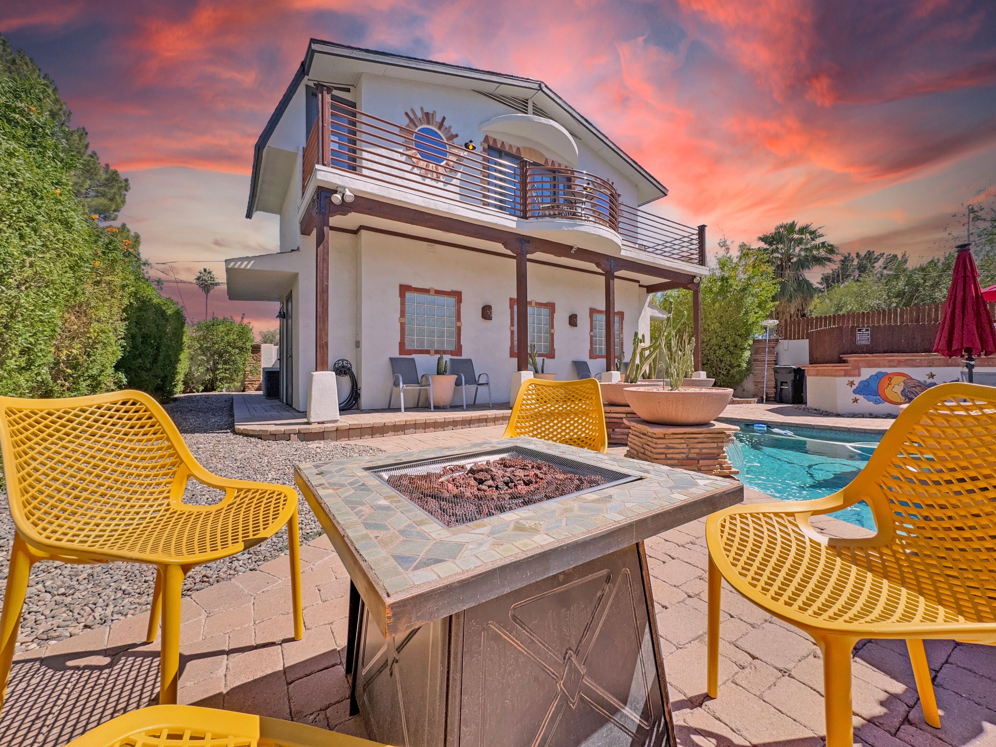 A two-story house with a balcony, outdoor seating, and a pool.