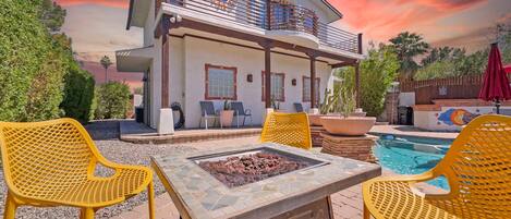 A two-story house with a balcony, outdoor seating, and a pool.