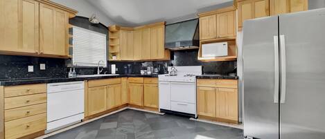 A modern kitchen with wooden cabinets, a stainless steel refrigerator, a dishwasher, and a gas stove.