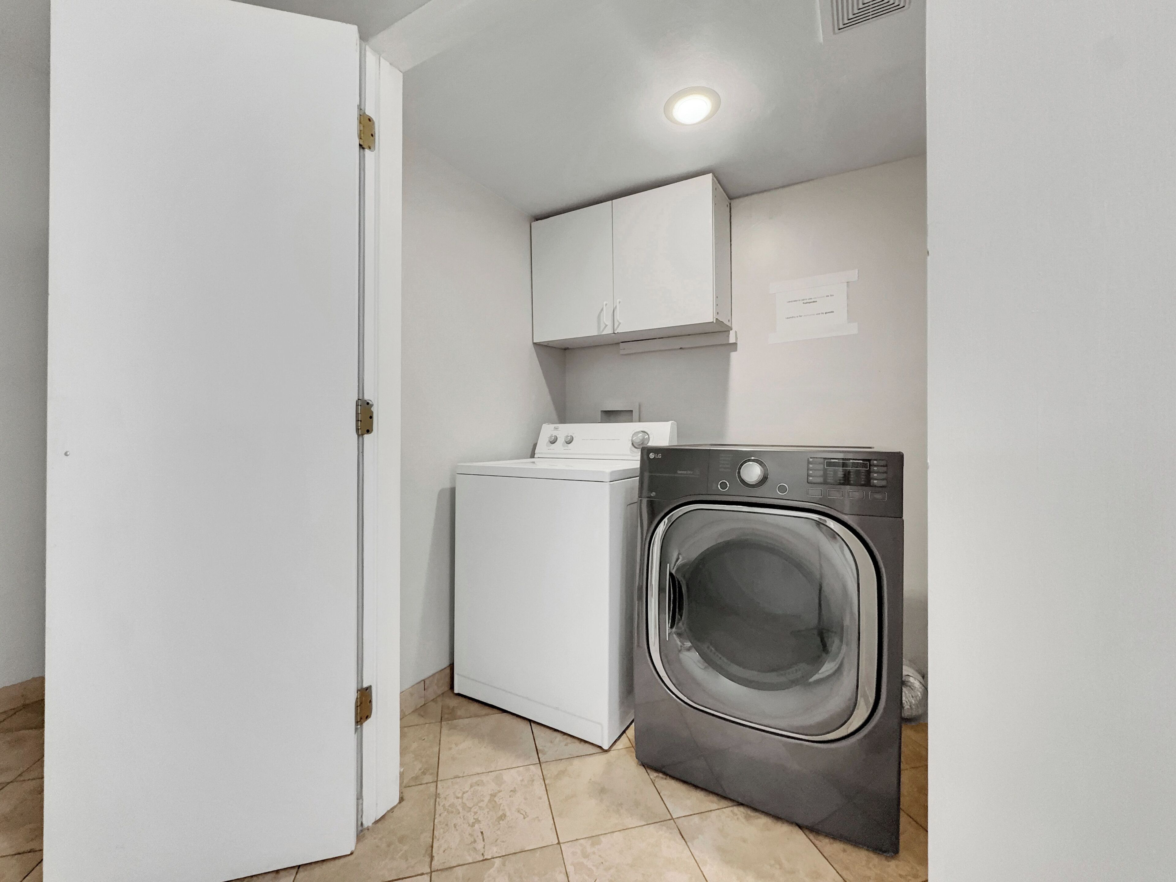 A laundry room with a washing machine, dryer, and cabinets.