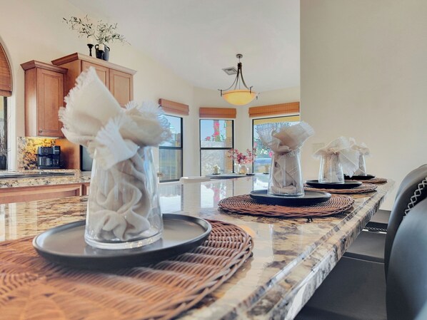 A kitchen with a marble countertop, wooden cabinets, and a hanging light fixture. - Oleander Ocotillo Chandler Complex (Chandler)