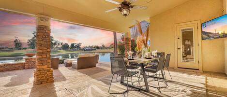 A patio with a dining table, chairs, and a ceiling fan.