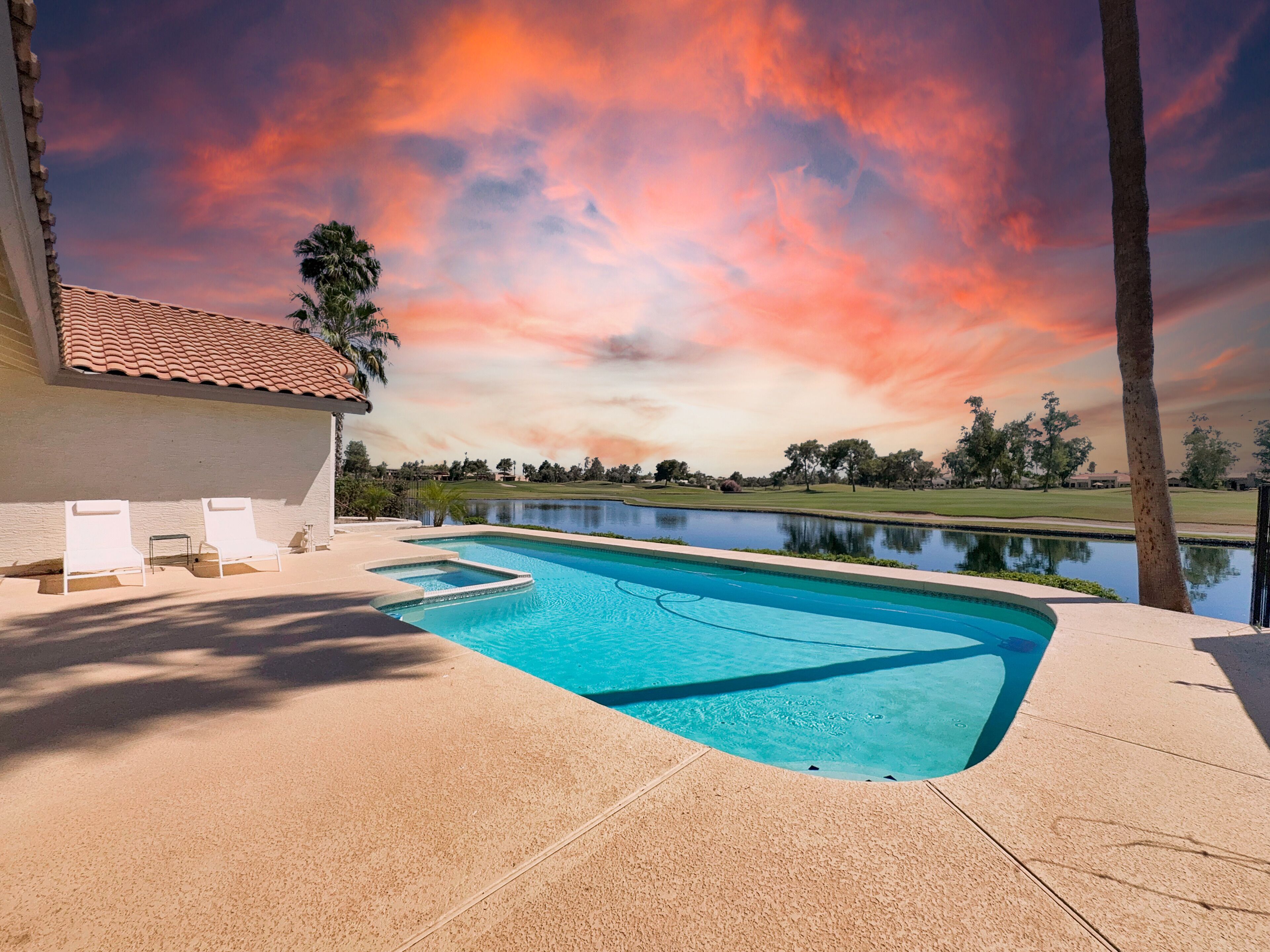 A swimming pool with a view of a lake and a sunset sky.