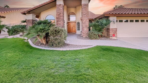 A house with a stone facade, a wooden front door, and a garage. - Oleander Ocotillo Chandler Complex (Chandler)