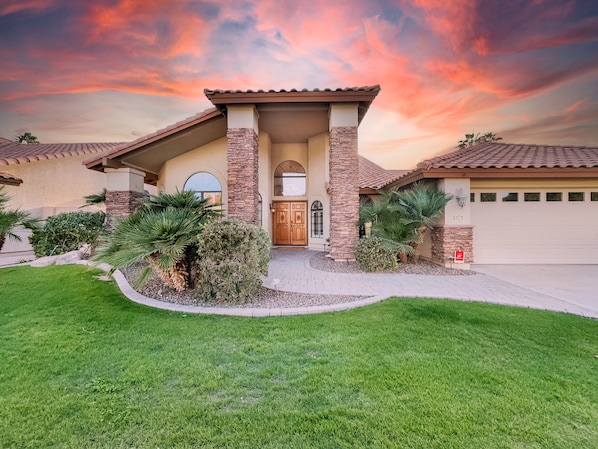 A house with a stone facade, a wooden front door, and a garage. - Oleander Ocotillo Chandler Complex (Chandler)