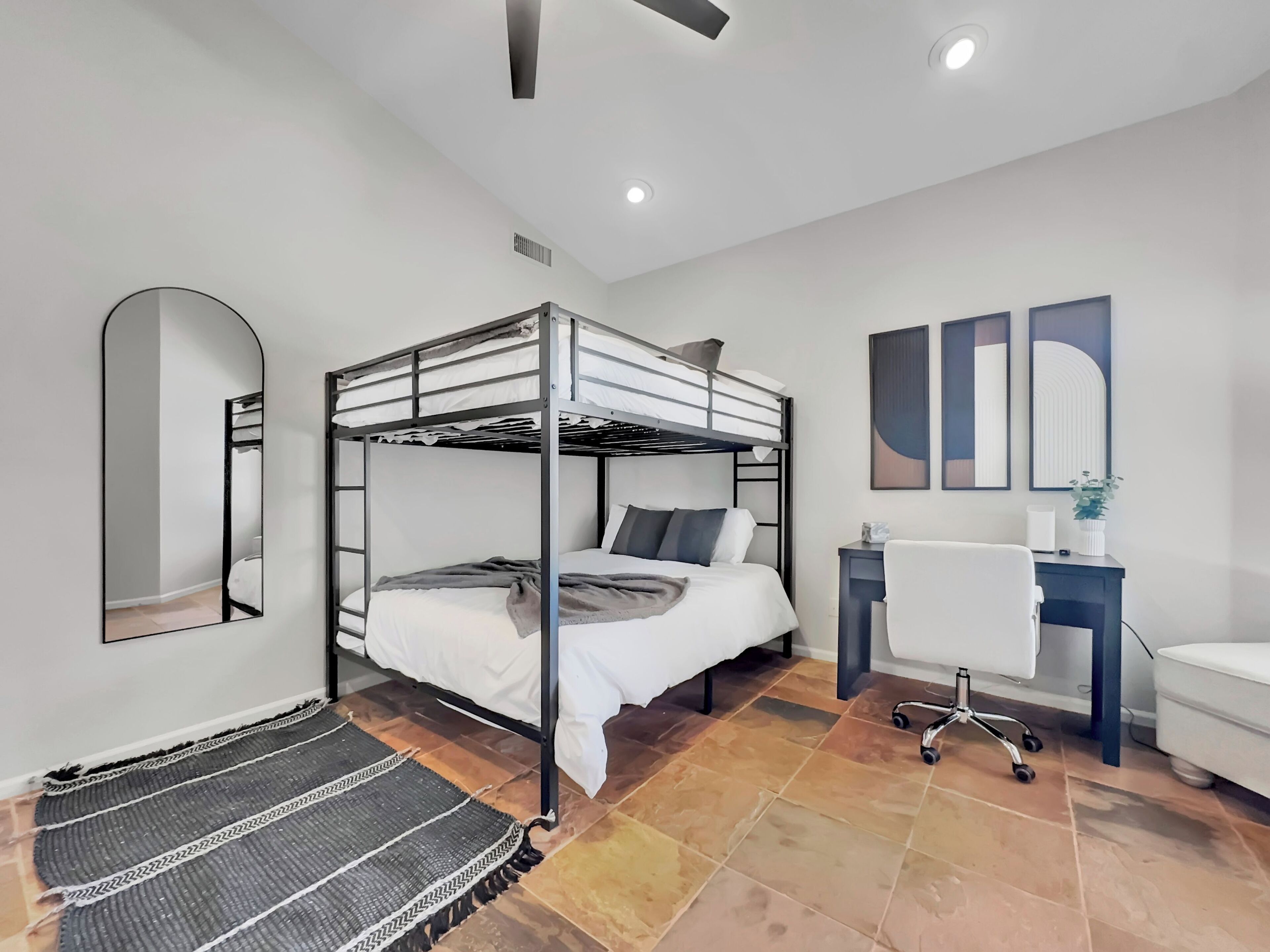 A modern bedroom with a bunk bed, a desk, and a chair.