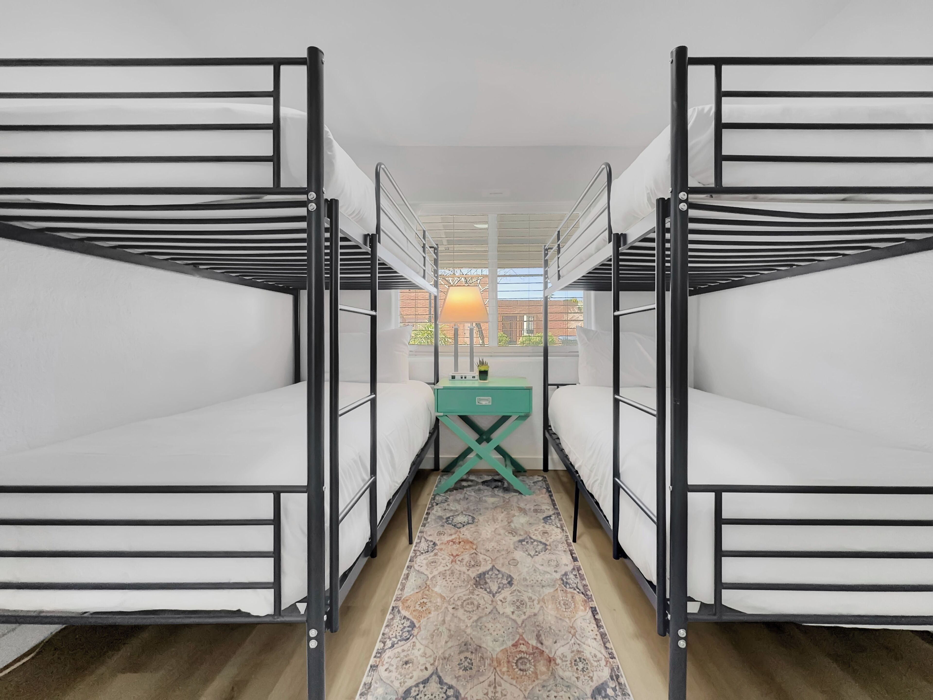 A room with bunk beds, a small table with a lamp, and a patterned rug.