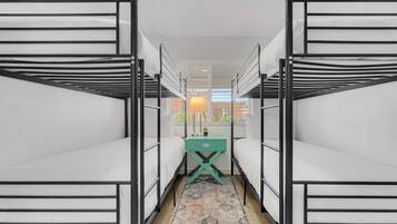 A room with bunk beds, a small table with a lamp, and a patterned rug.