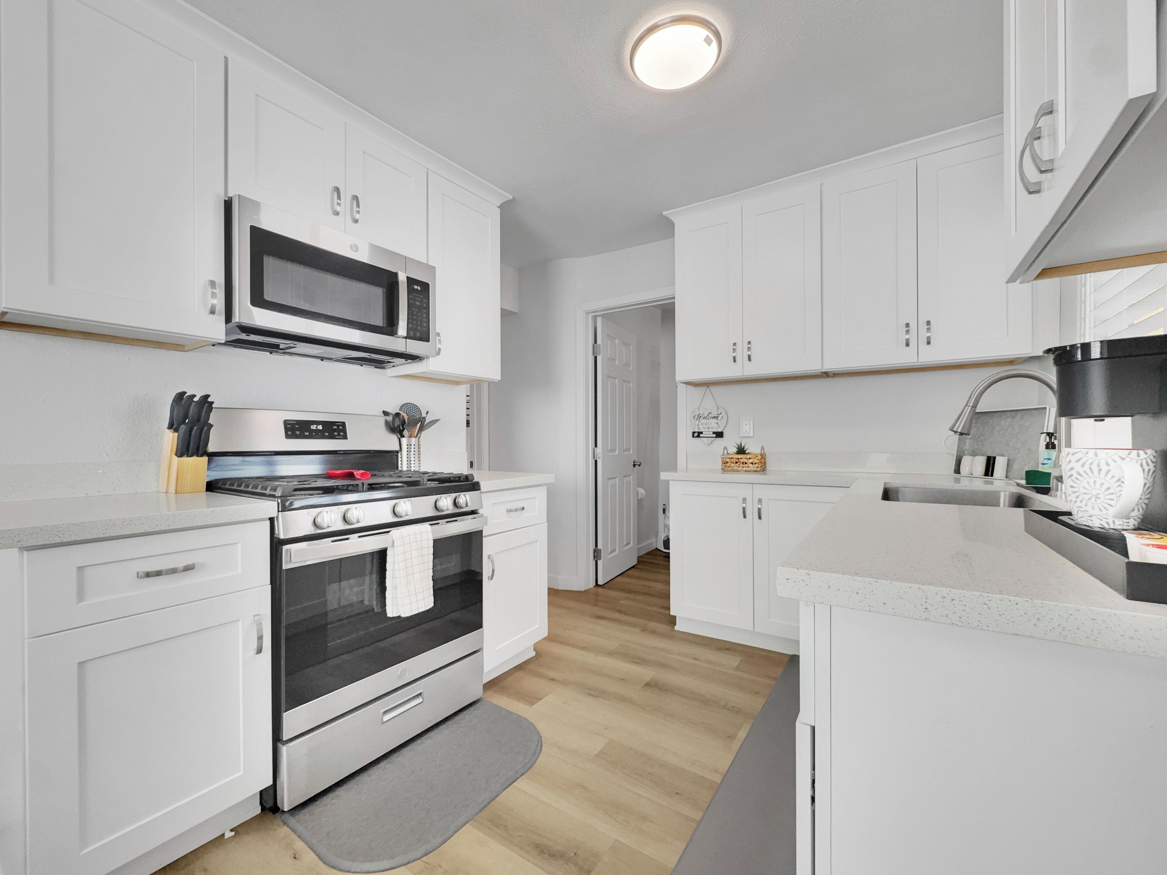 A modern kitchen with white cabinets, a stainless steel stove, and a microwave.