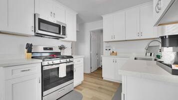 A modern kitchen with white cabinets, a stainless steel stove, and a microwave.