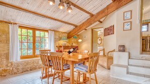A rustic dining area with a wooden table and chairs, stone walls, and a wooden ceiling. - La Bergerie – Charming House with Shared Pool (Le Buisson-de-Cadouin)
