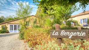 A rustic stone building with a gravel driveway and a wooden sign reading 'La Bergerie.' - La Bergerie – Charming House with Shared Pool (Le Buisson-de-Cadouin)