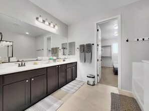 Een moderne badkamer met een grote spiegel, een dubbele wastafel en een inloopdouche.