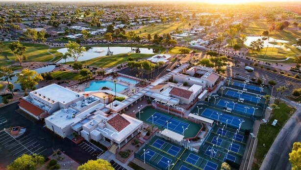 A residential area with multiple tennis courts, a swimming pool, and a golf course in the background. - Flame Tree Sun Lakes (Chandler)