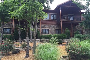 A log cabin with a stone foundation, multiple windows, and a balcony. - Stonewater Cove (Shell Knob)