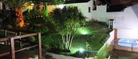 Une vue nocturne d’un quartier résidentiel avec un escalier, une piscine et des espaces verts bien éclairés.